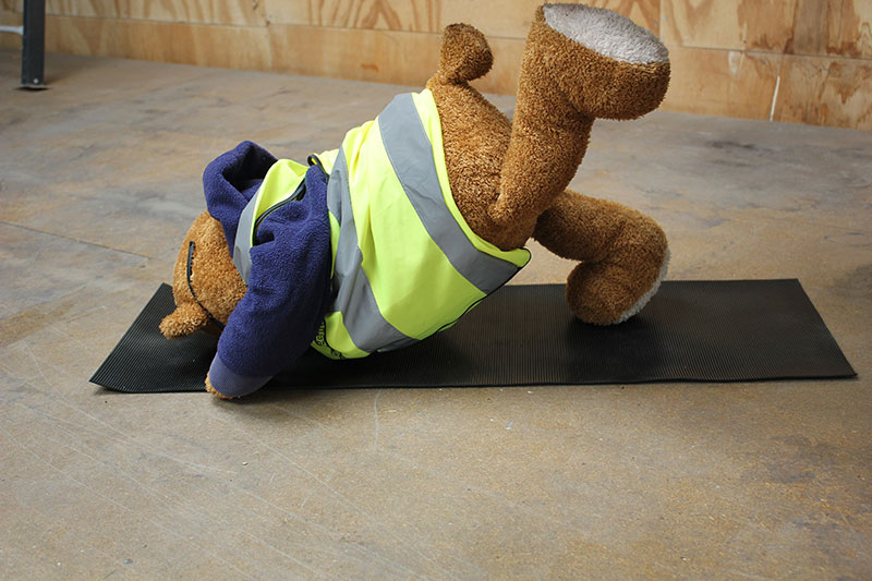 Health and Safety Bear demonstrates Leg High Yoga Pose