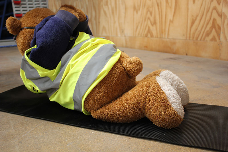 Health and Safety Bear demonstrates the Locust Yoga Pose