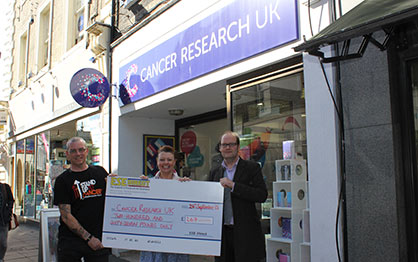 Martin Donovan and Martin Gilmour present the cheque to the manager of the Cancer Research Charity Shop, Norwich