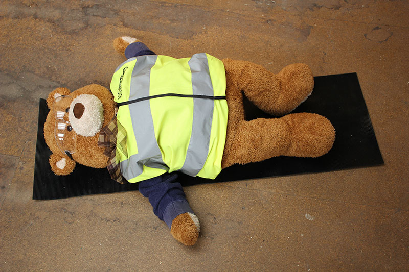 Health and Safety Bear demonstrates Shavasana Yoga Pose